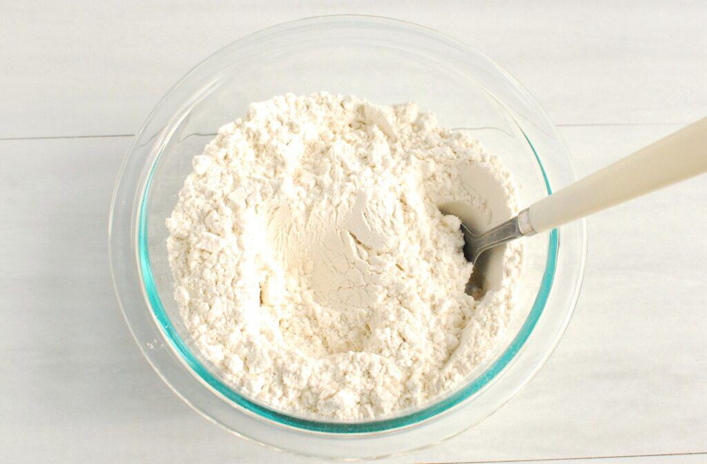 Flour, baking soda, salt, and rosemary mixed together in a bowl.