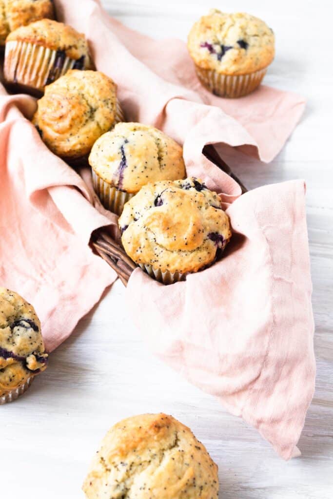 A basket holding dairy free lemon poppyseed blueberry muffins.