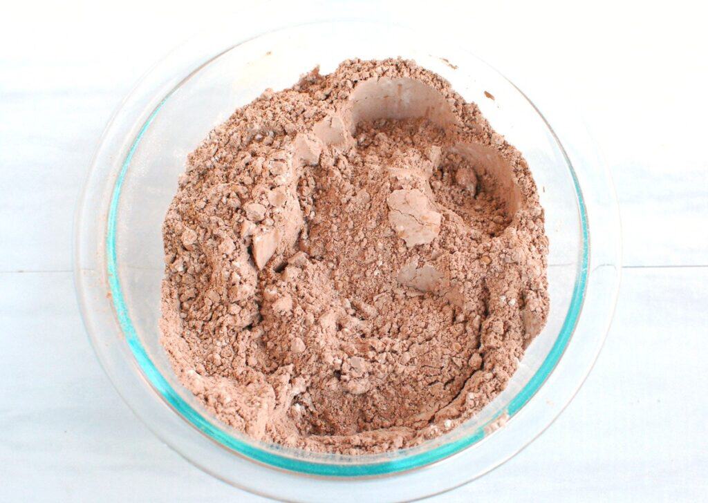 Flour, cocoa powder, baking powder, baking soda, and salt mixed together in a bowl.