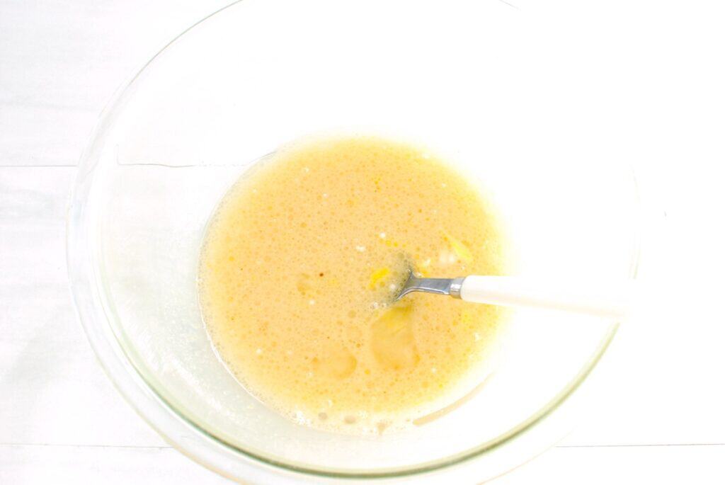 Almond milk, sugar, oil, egg, and vanilla mixed together in a bowl.