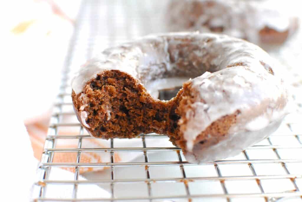 A dairy free chocolate donut with a bite taken out of it, showing the soft interior texture.