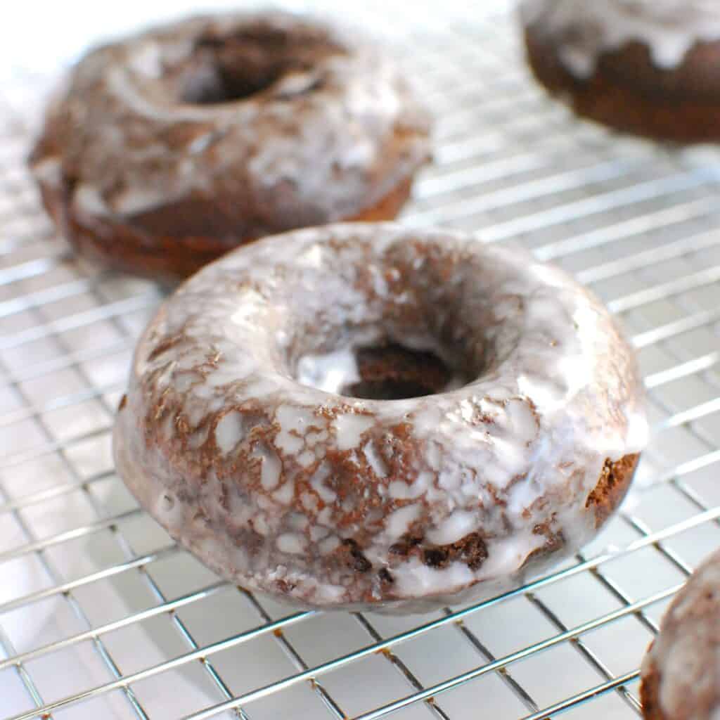 A dairy free chocolate glazed donut on a cooling rack.