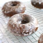 A dairy free chocolate glazed donut on a cooling rack.