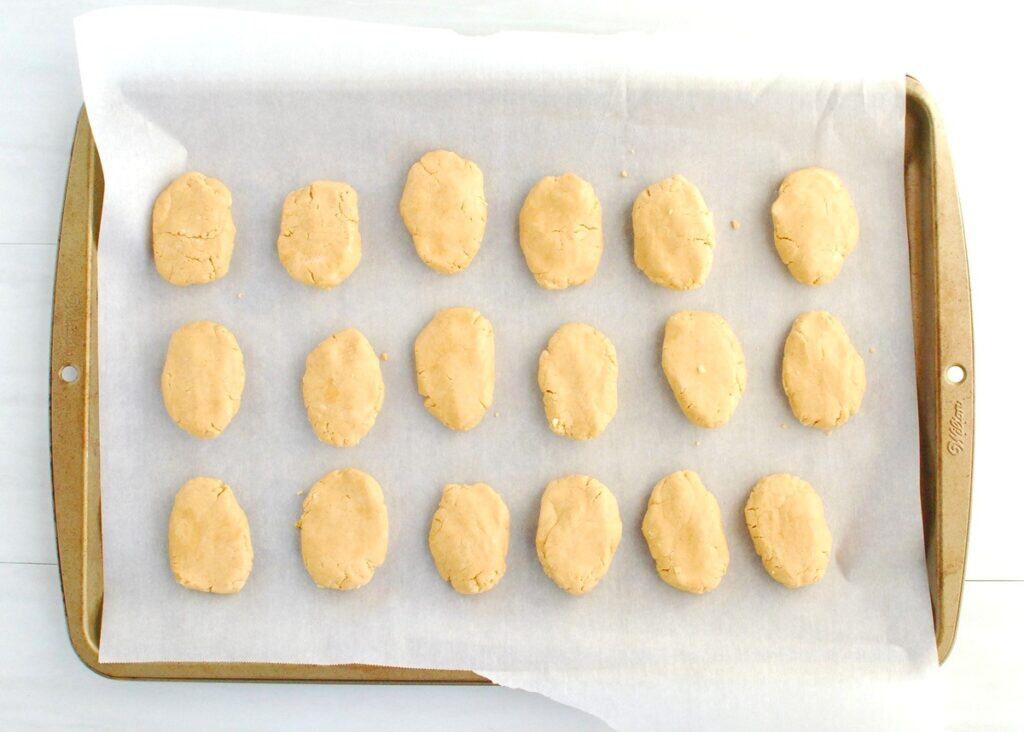 Peanut butter filling shaped like eggs, lined up on parchment paper.