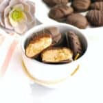 Several dairy free chocolate peanut butter eggs in a bowl, with one split in half showing the peanut butter filling.