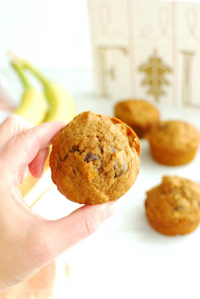 A woman's hand holding a dairy free banana pumpkin muffin.