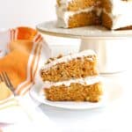 A slice of dairy free carrot cake on a plate next to a fork and napkin.