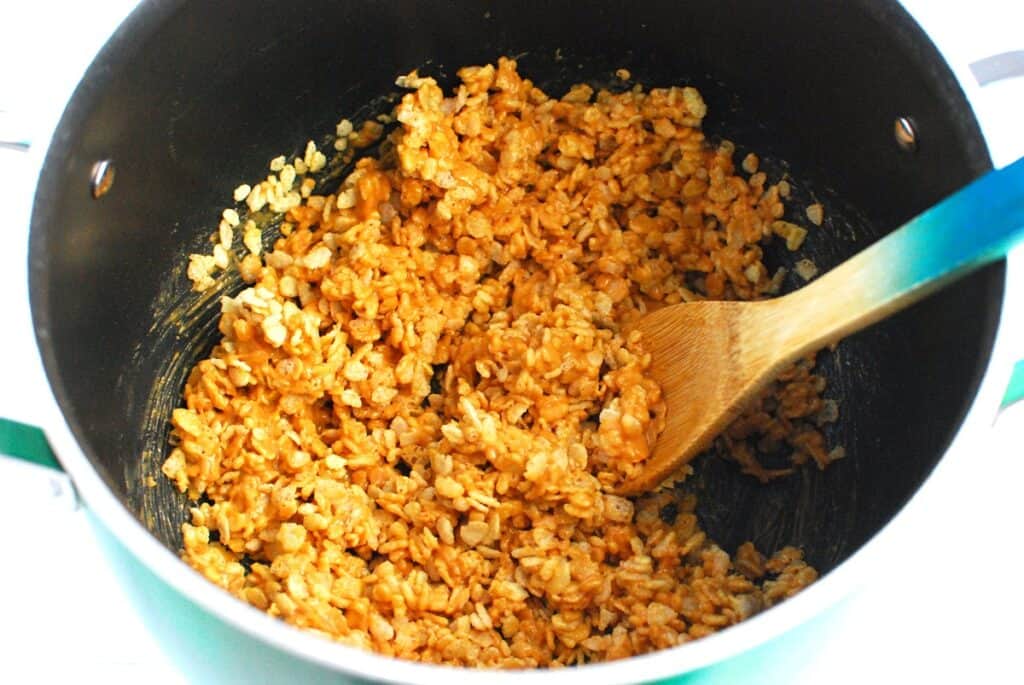 Rice cereal stirred into the peanut butter mixture in the pot.