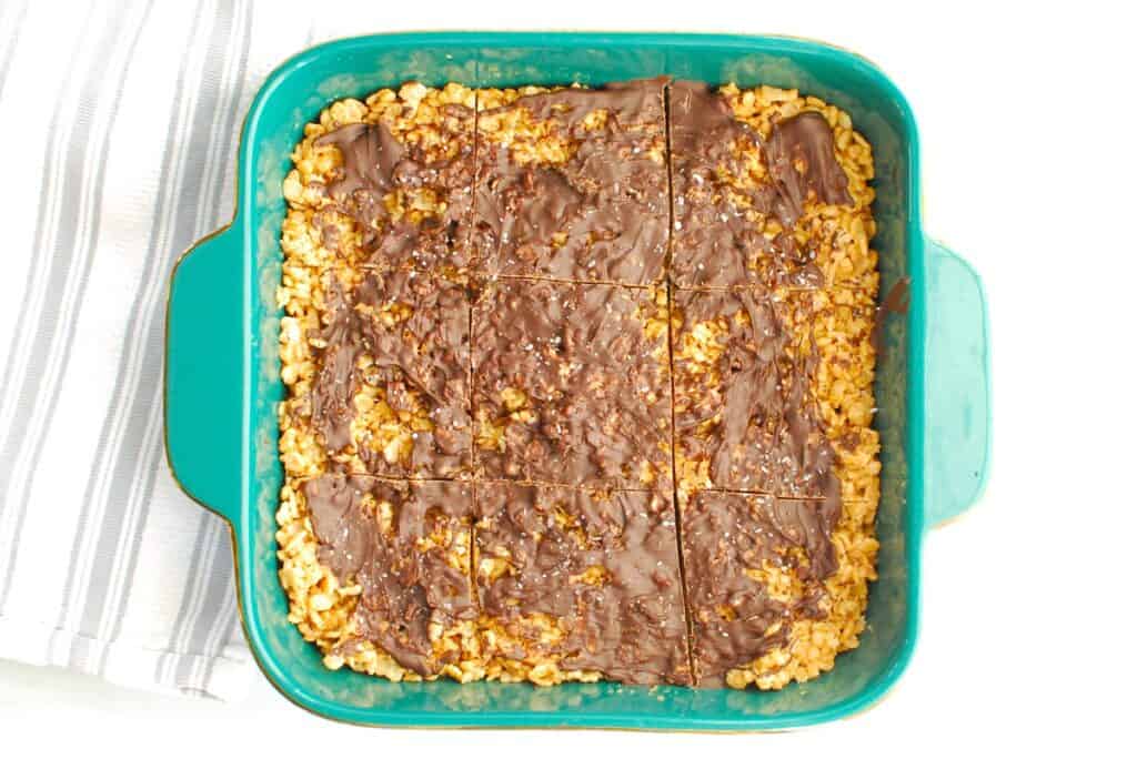 A baking dish with 9 chocolate peanut butter rice crispy squares cut in it.