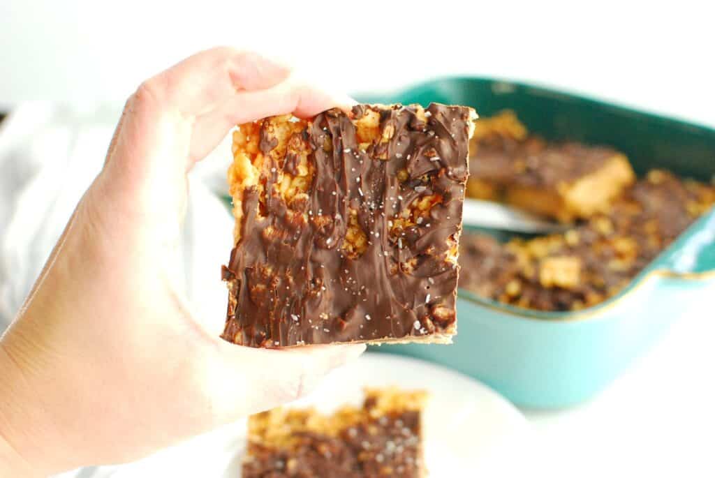 A woman's hand holding a peanut butter rice krispie square.