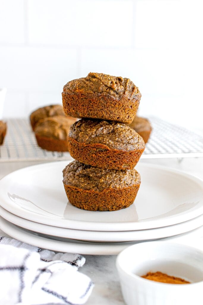 Three buckwheat pumpkin muffins stacked on a plate.