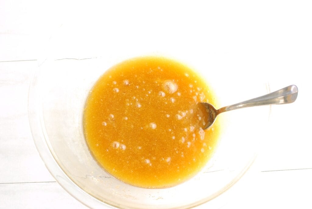 Browned dairy-free butter, brown sugar, granulated sugar, egg, and vanilla extract mixed together in a glass bowl.