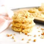 A stack of three dairy free butter pecan cookies on a white table.
