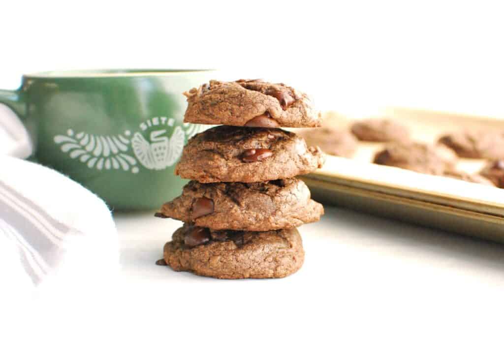 A stack of dairy-free brownie mix cookies with a mug of dairy-free milk in the background.