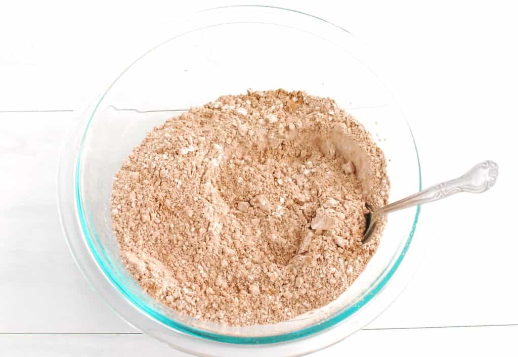 Flour, cocoa powder, baking soda, and salt mixed together in a glass bowl.