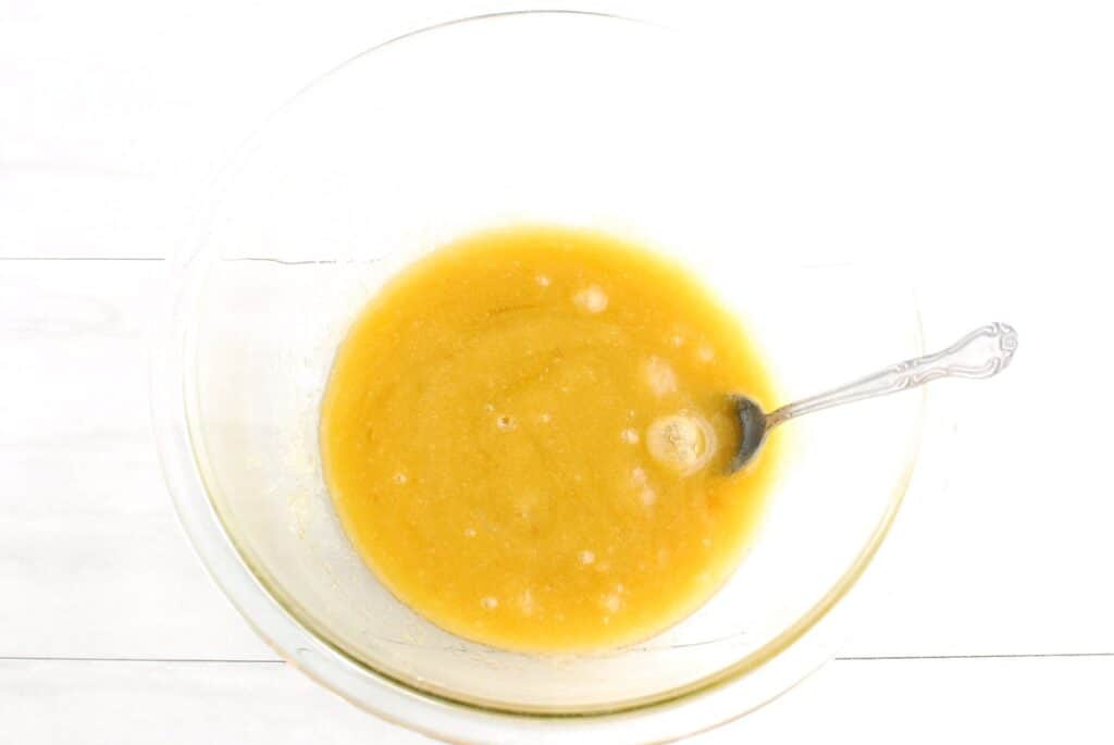 Olive oil, brown sugar, granulated sugar, egg, and vanilla mixed together in a glass bowl.