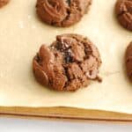 A double chocolate olive oil cookie on a baking sheet lined with parchment paper.