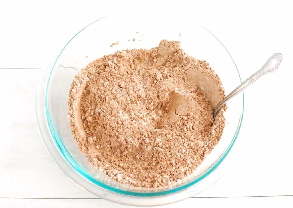 Flour, cocoa powder, baking soda, and salt mixed together in a glass bowl.