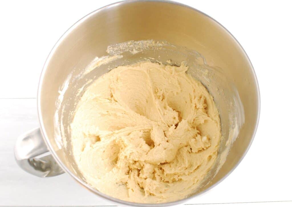 Dairy-free butter, sugar, brown sugar, egg, and vanilla mixed together in a silver bowl.