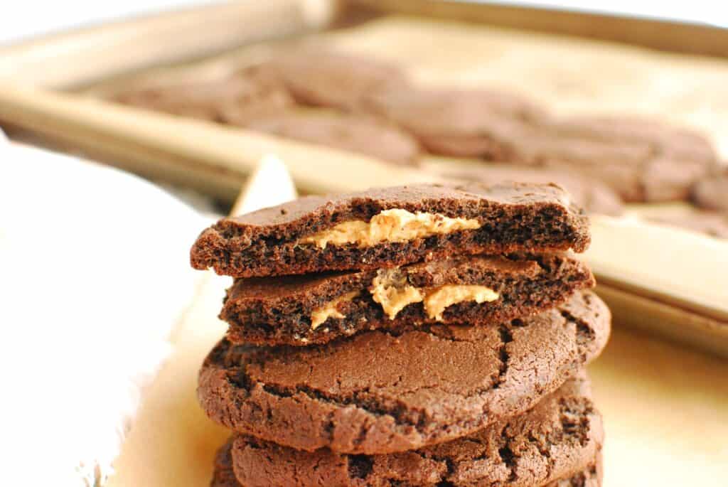 A chocolate cookie broken in half showing it's stuffed with peanut butter.