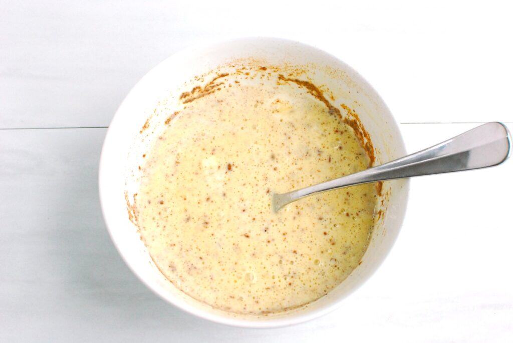 Melted ice cream, eggs, and cinnamon whisked together in a bowl.