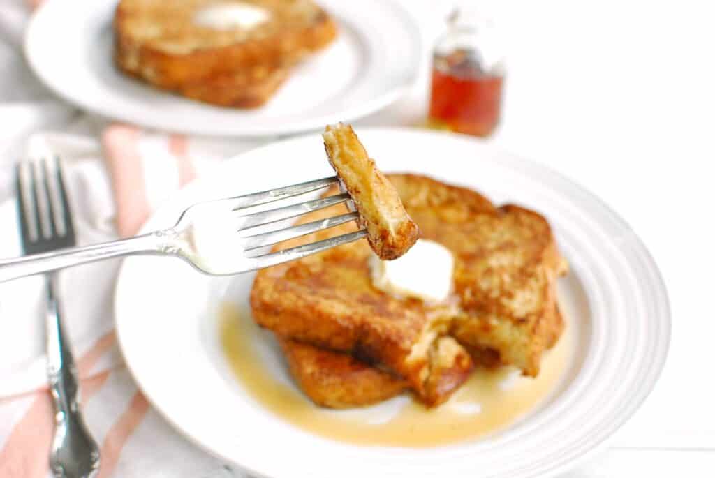 A fork with a piece of french toast on it.
