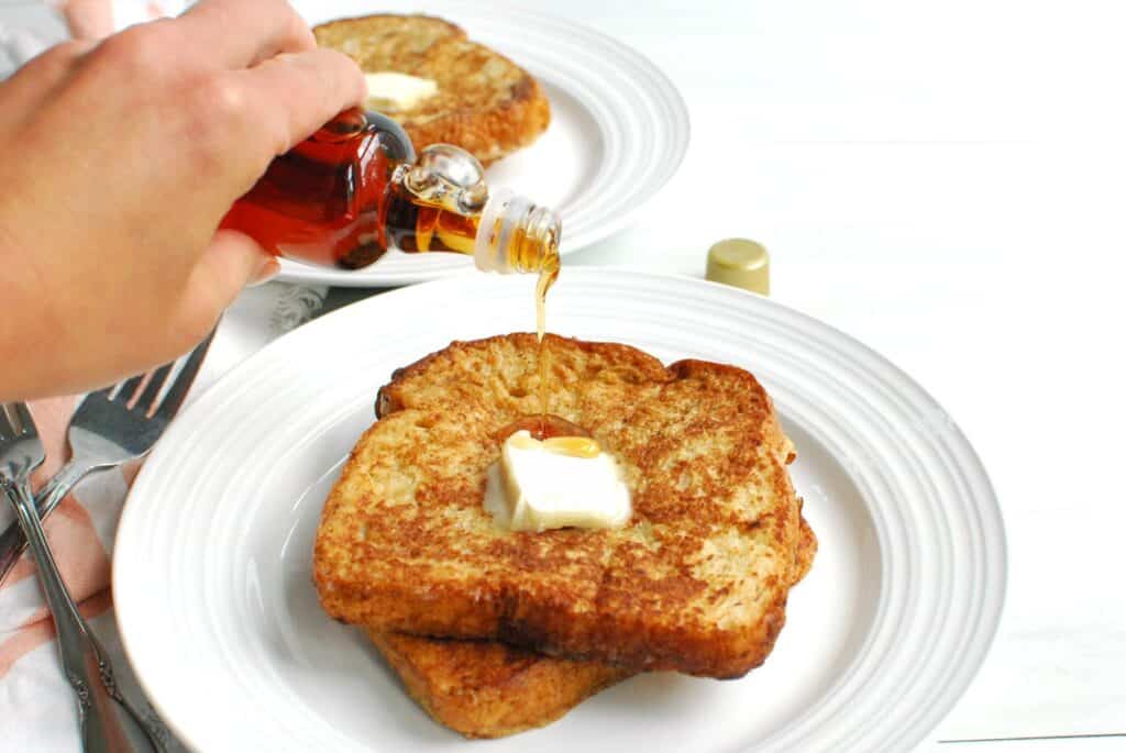 Two slices of dairy free ice cream french toast being drizzled with maple syrup.