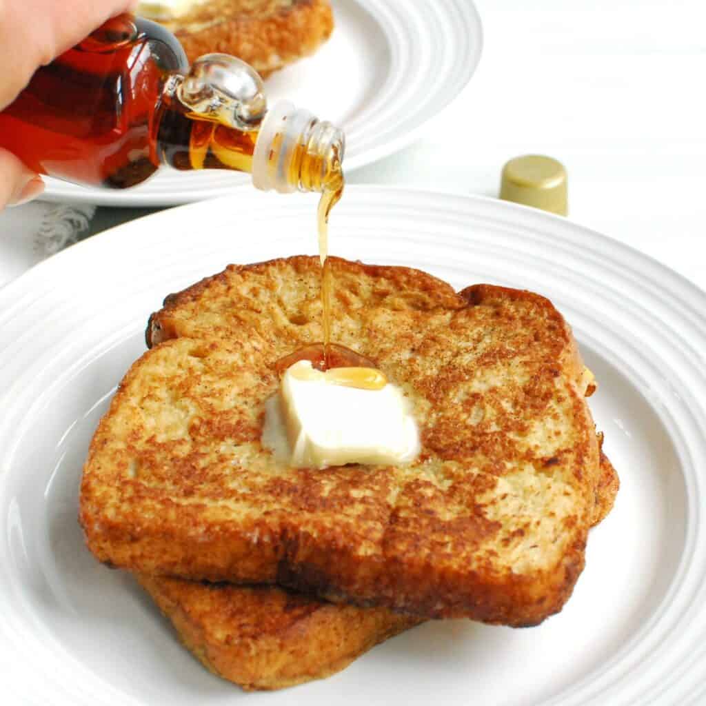 Two slices of dairy free ice cream french toast being drizzled with maple syrup.