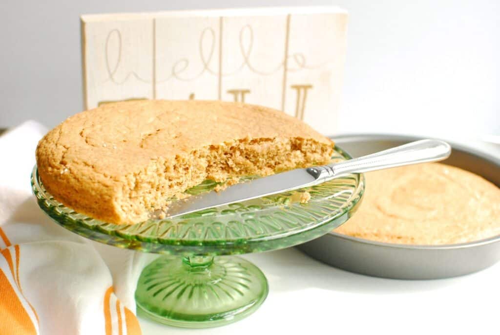 A spice cake on a cake stand with some slices cut out.