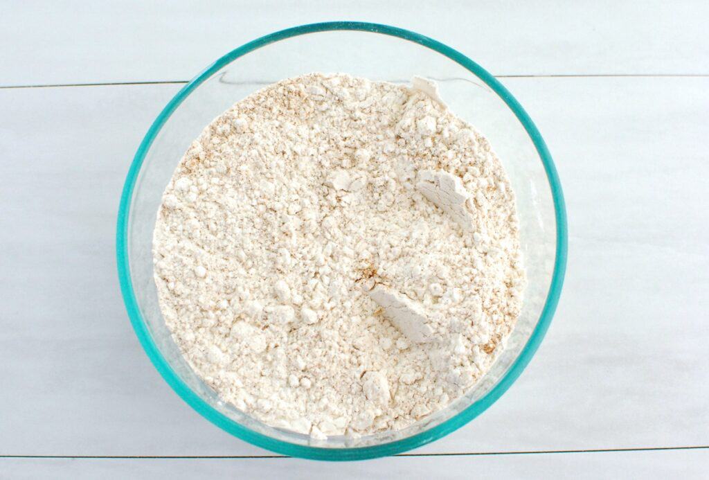 Flour, cinnamon, cloves, baking soda, and salt in a glass bowl.