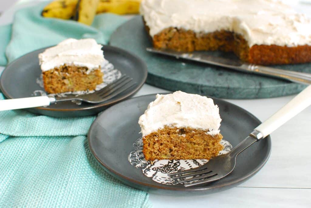 Two slices of dairy free banana cake on plates with forks.