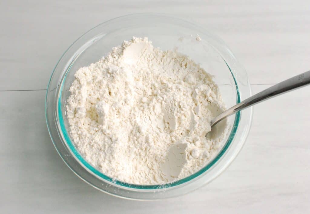 Flour, baking soda, and salt mixed together in a glass bowl.