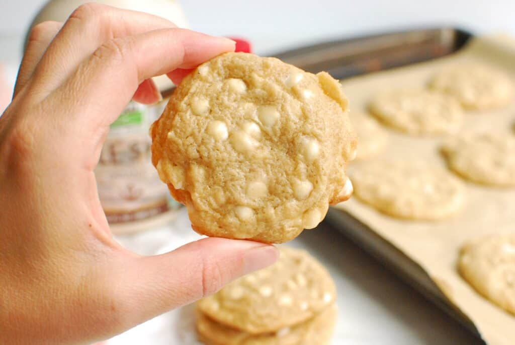 A woman's hand holding a dairy free maple white chocolate cookie.
