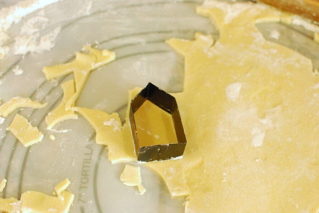 A cookie cutter cutting out cookie dough on a floured surface.