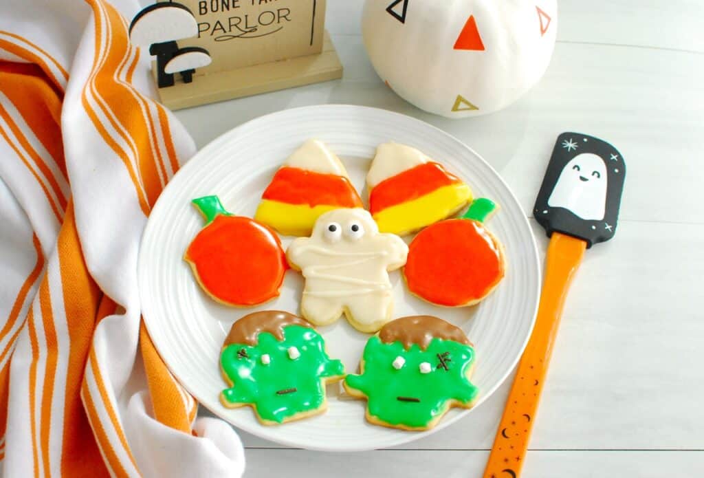 A plate with a bunch of dairy free Halloween sugar cookies decorated with powdered sugar icing.