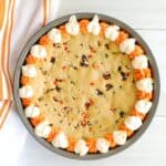 Overhead shot of an oil-based Halloween cookie cake decorated with orange and white frosting.