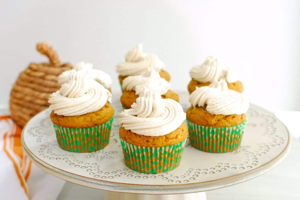A bunch of dairy free pumpkin cupcakes on a cake stand.