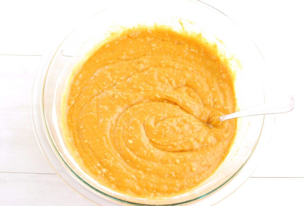Pumpkin muffin batter in a glass mixing bowl.