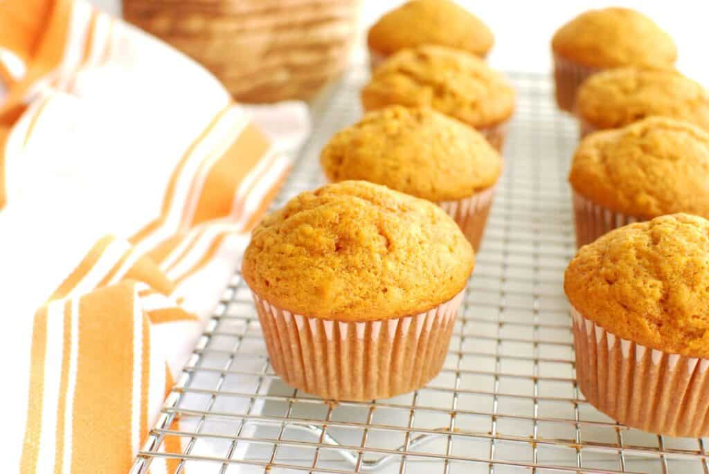 A bunch of dairy free pumpkin muffins on a cooling rack.
