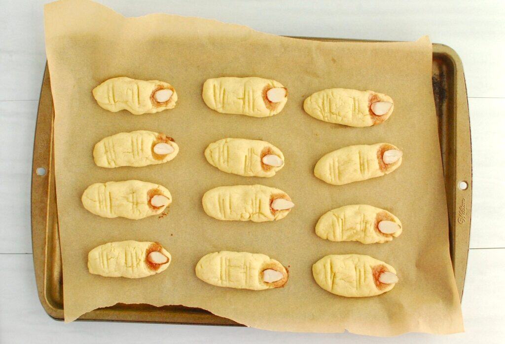 Just baked Halloween finger cookies on a baking sheet.