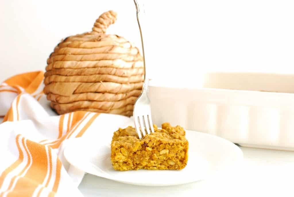 A piece of maple pumpkin oatmeal bake on a plate with a fork stuck into the middle.
