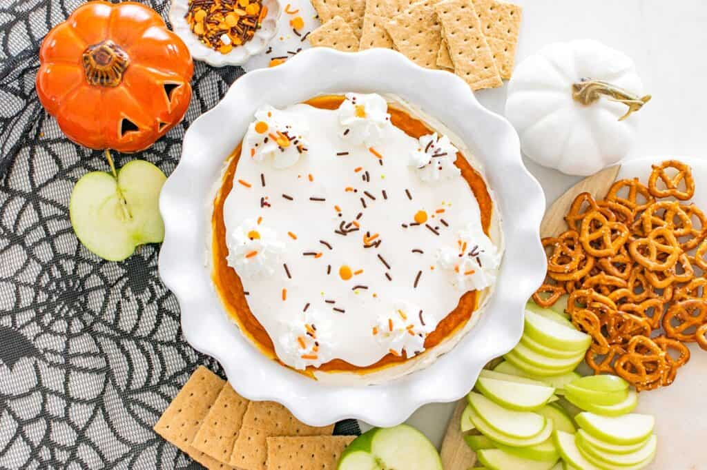 A pie plate with dairy-free pumpkin cheesecake dip surrounded by dippers like graham crackers and apples.