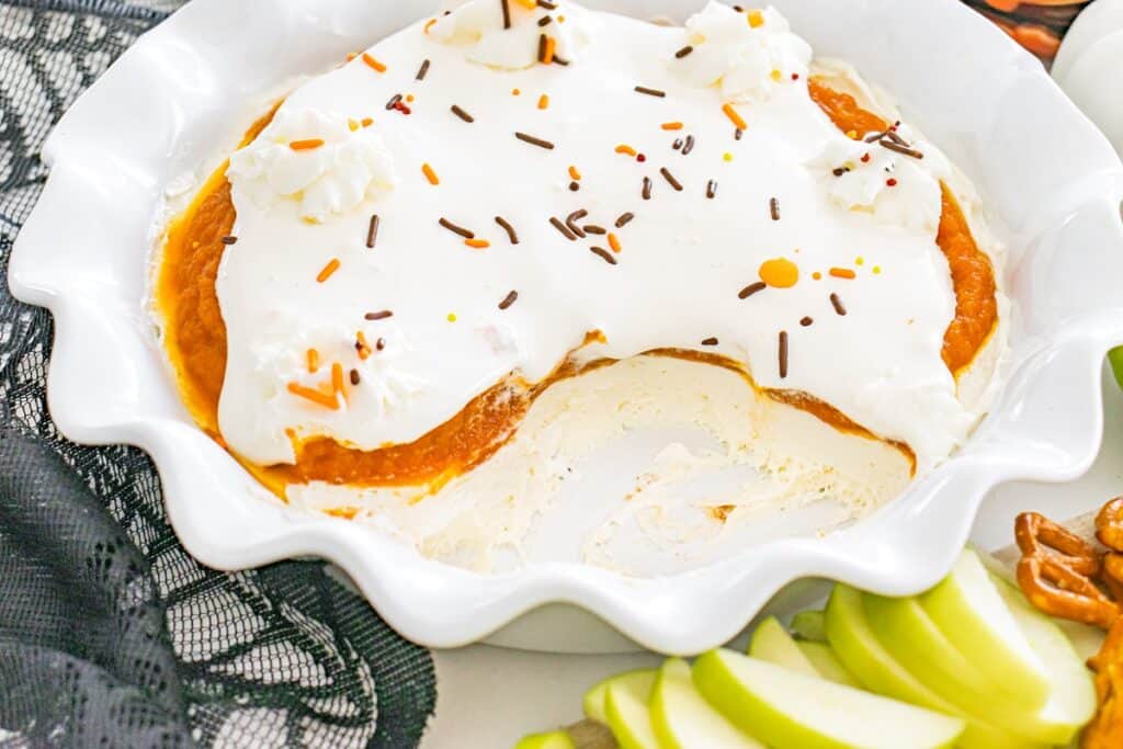 Dairy-free pumpkin cheesecake dip in a pie plate with some scoops already taken out.
