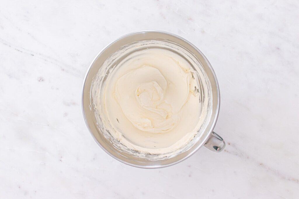 Dairy-free cream cheese, dairy-free frozen whipped topping, and powdered sugar combined in a mixing bowl.
