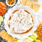 A pie plate full of dairy-free pumpkin cheesecake dip surrounded by apples, graham crackers, and pretzels.