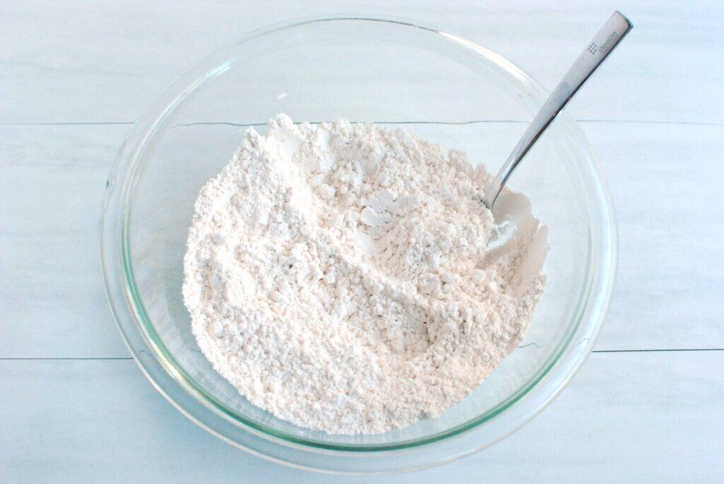 Flour, baking powder, baking soda, and salt mixed together in a bowl.