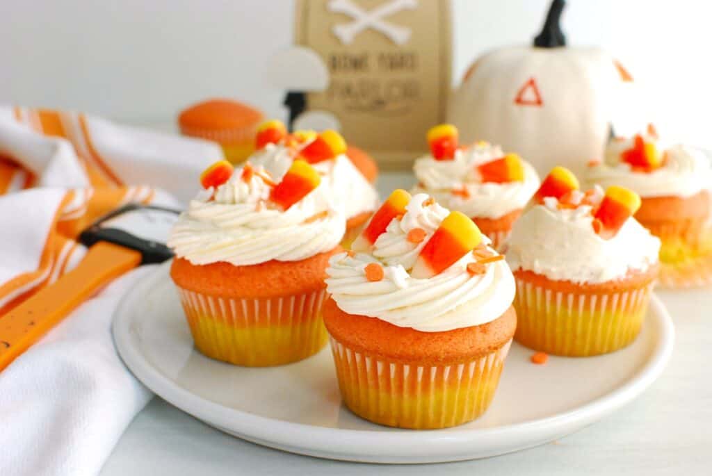 Several candy corn cupcakes on a plate.