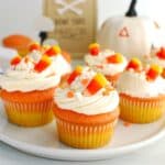 Several candy corn cupcakes on a white plate.