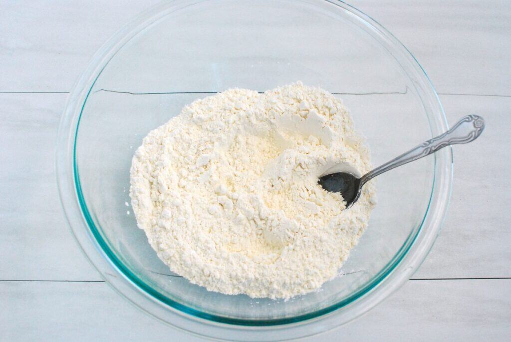 Flour, sugar, baking powder, and salt combined in a glass mixing bowl.