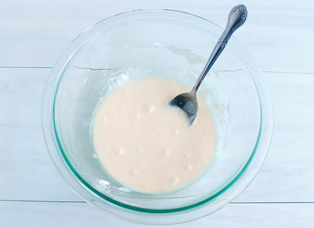 Powdered sugar, oat milk, and vanilla combined in a glass bowl to make icing.